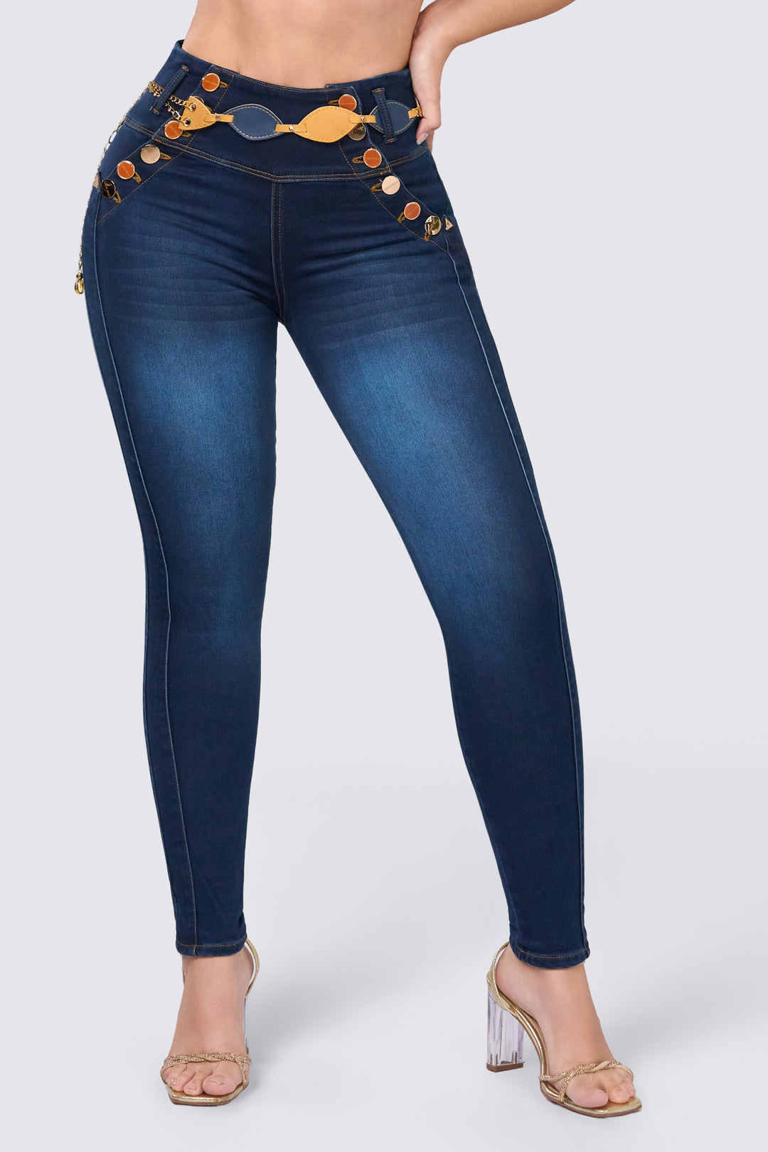 Skinny jeans azul oscuro, tiro alto, con botones frontales y cinturón decorativo.
