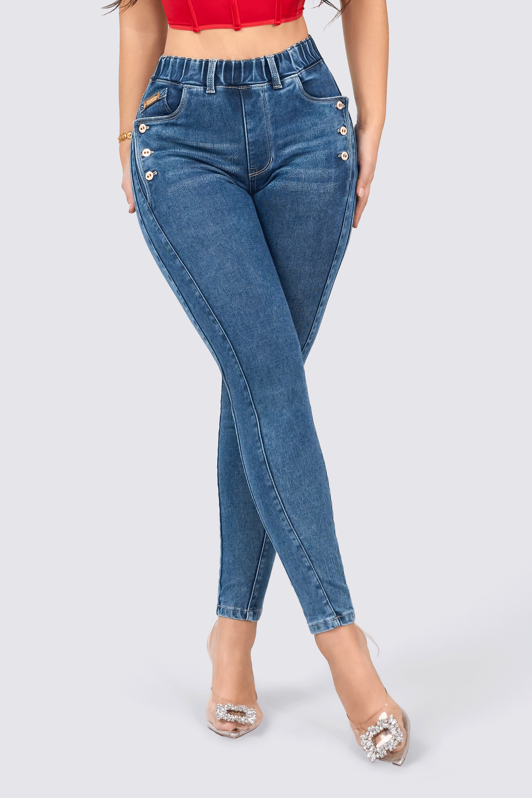 Skinny jeans de color azul, de tiro alto con cintura elástica, botones decorativos y bolsillos traseros funcionales. 