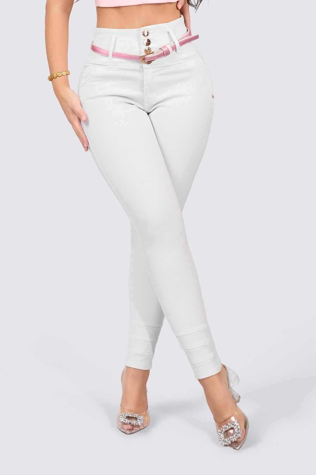 Skinny jeans color blanco con bolsillos traseros, tiro alto y cinturón fino rosado. 