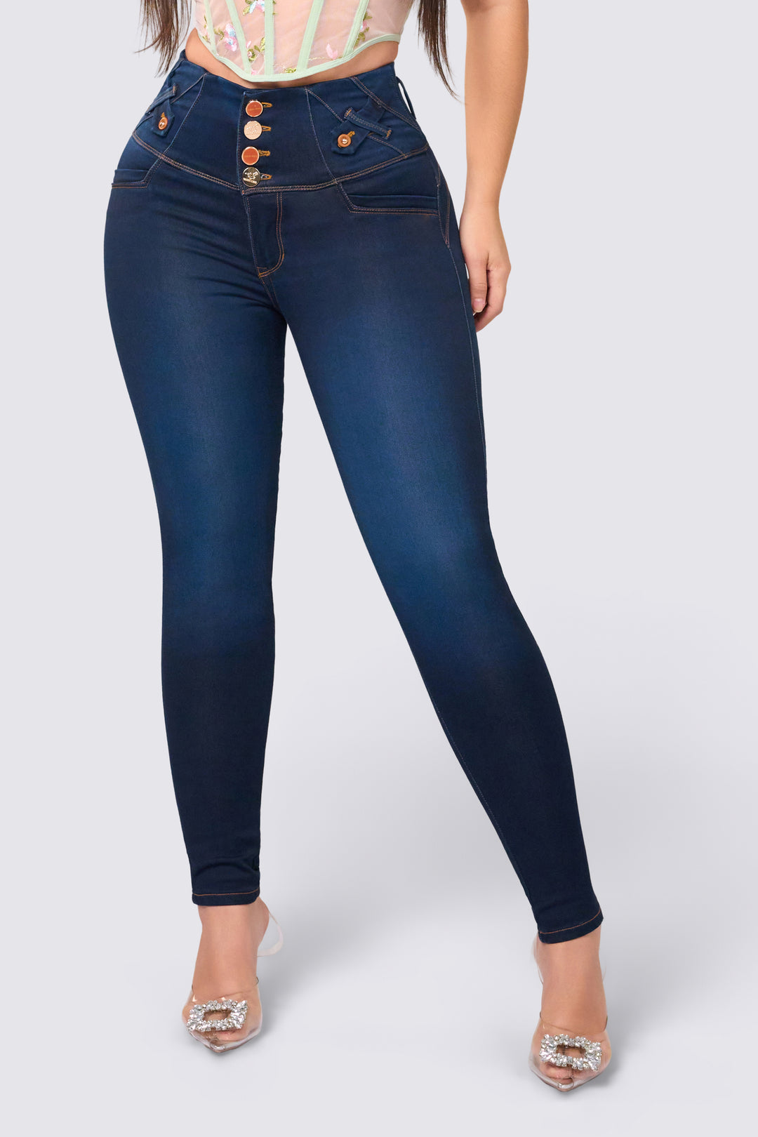 Skinny jean de color azul oscuro, con pretina ancha, cuatro botones dorados y costuras que realzan el diseño del jean.